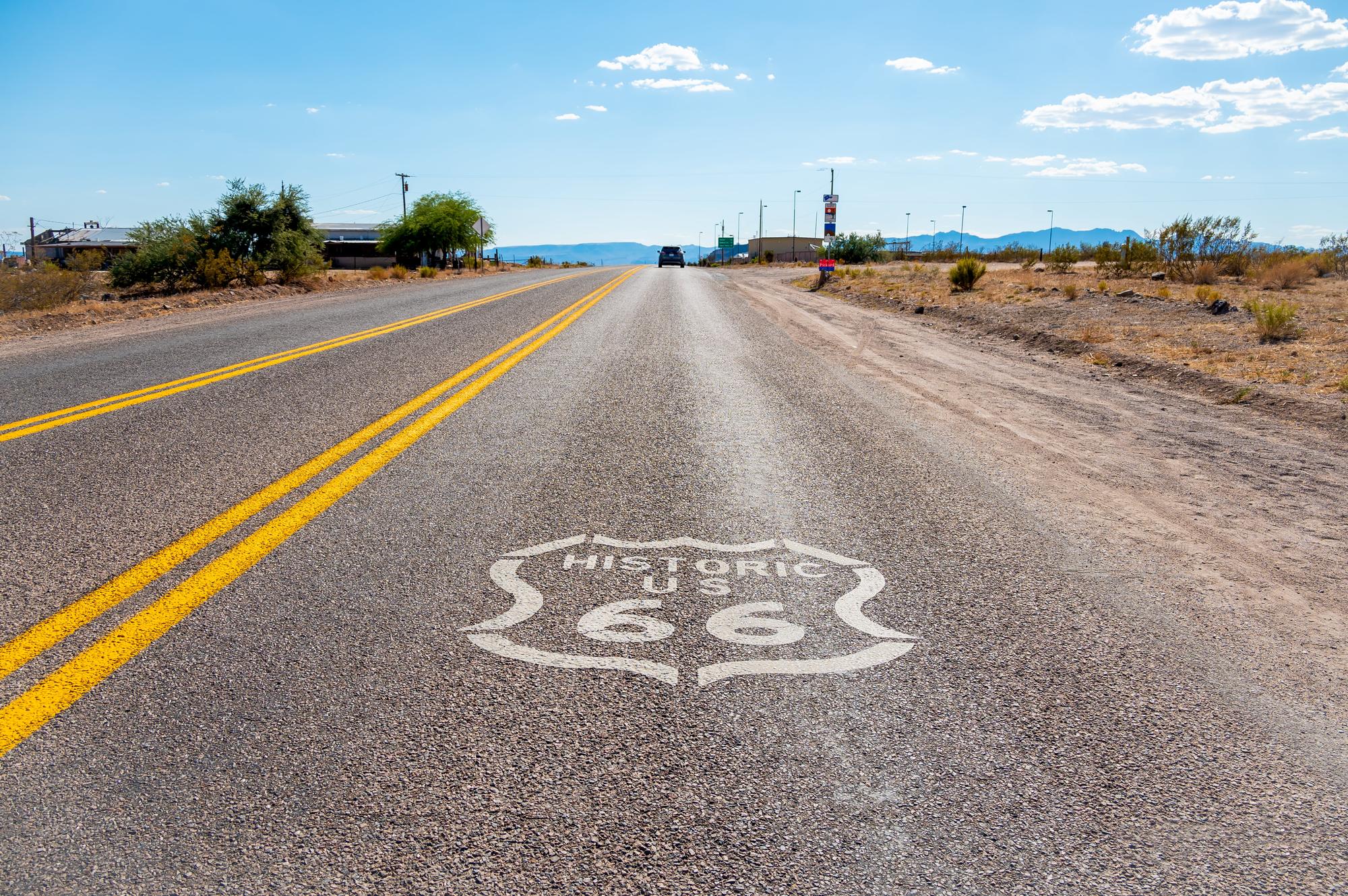 White route 66 shield painted on a road that stretches into the horizon