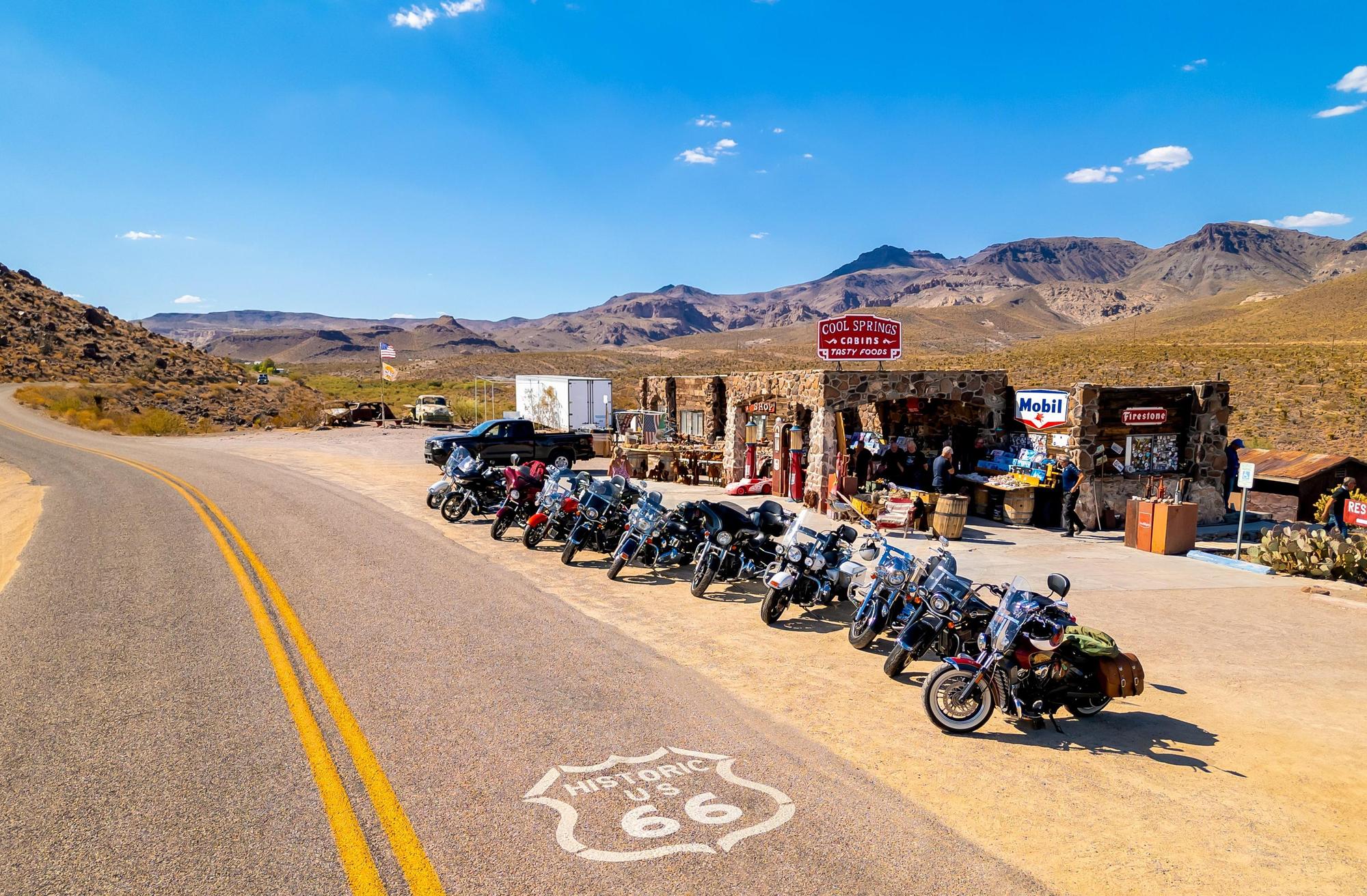 Cool Springs along Route 66 on the way to Oatman, Arizona. 11 motorcycles line the road in front of the roadside attraction white a white route 66 shield painted on the road.