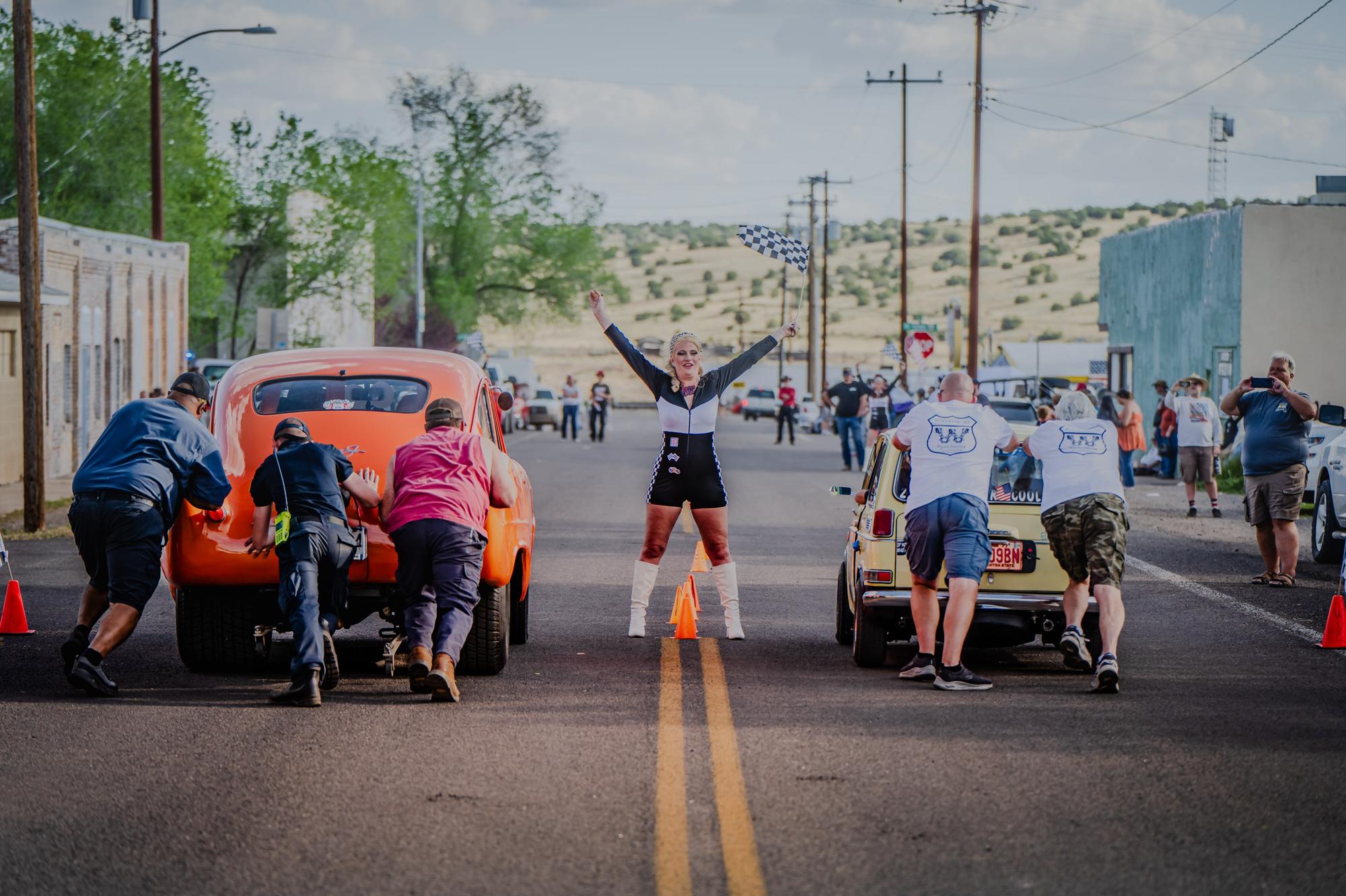 men pushing two classic cars in a 