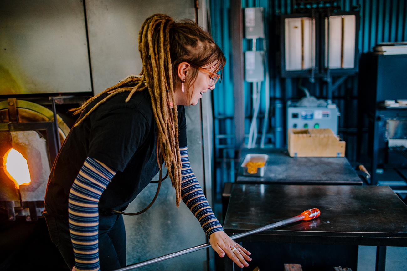Woman holding molten glass in a furnace